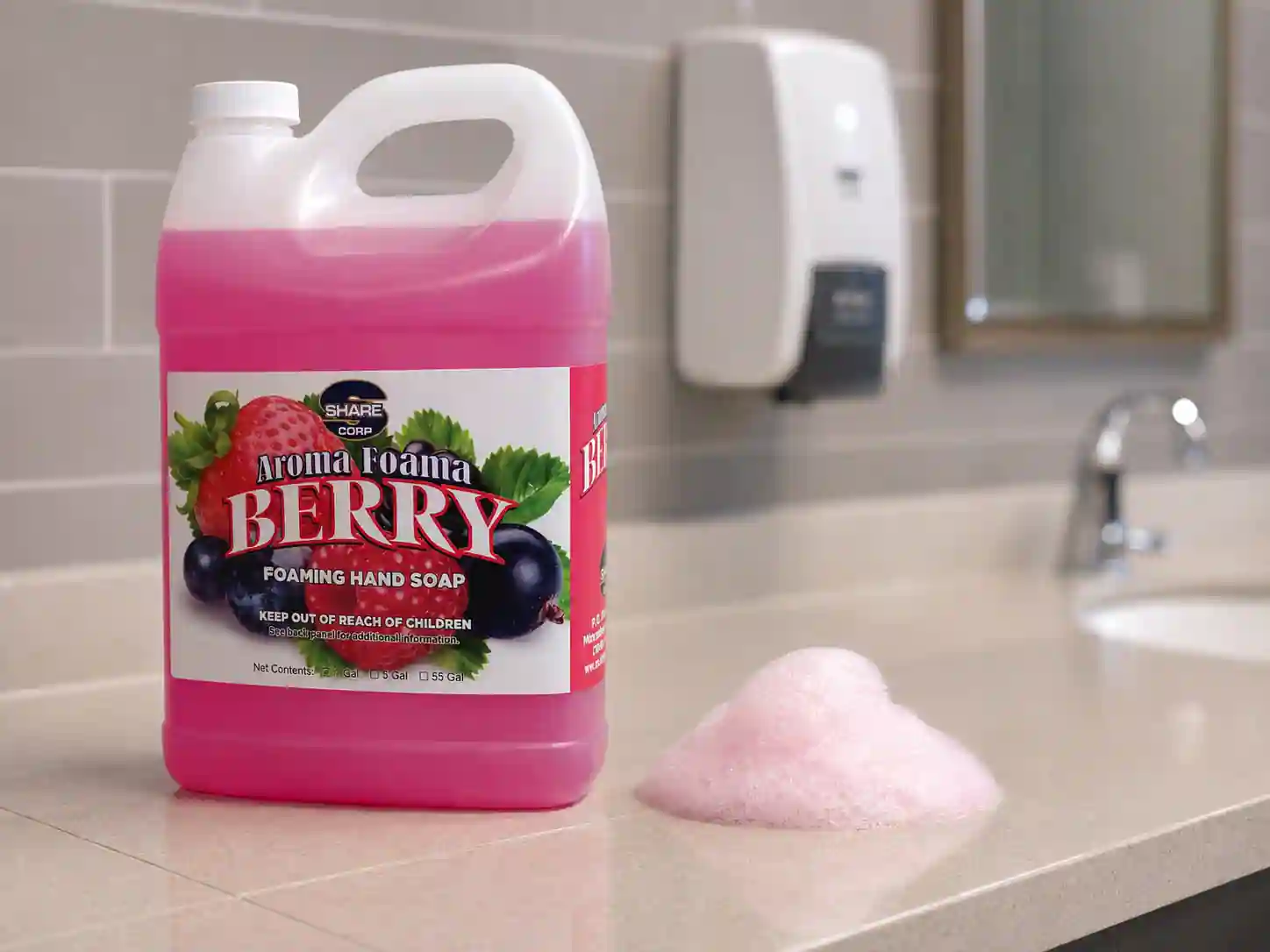 AROMA FOAMA BERRY one-gallon soap jug next to a wall-mounted foam dispenser above a restroom sink